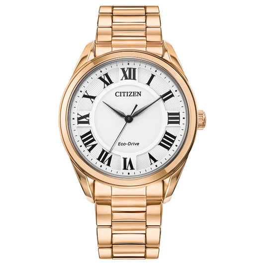 The CITIZEN Fiore Eco-Drive 32mm Watch by CITIZEN highlights its Eco-Drive technology, presenting a white dial adorned with black Roman numerals and hour and minute hands. This sophisticated timepiece is elegantly designed with a gold metal bracelet and a crown on the right side, ideal for anyone desiring sophistication in their accessories.