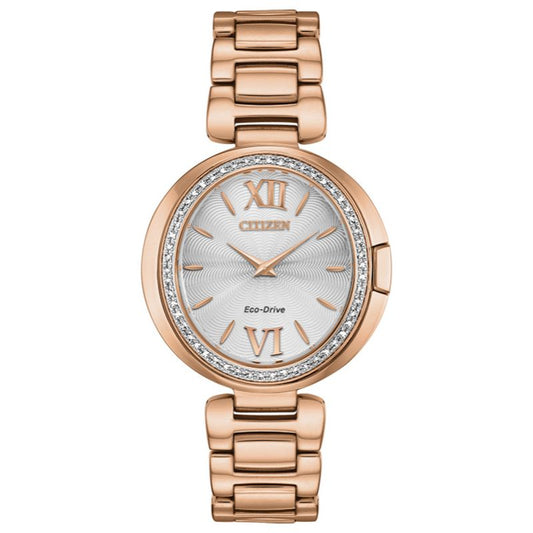 Introducing the CITIZEN Capella Eco Drive 34mm Watch, an elegant timepiece from the renowned CITIZEN brand. This stunning gold-tone watch boasts a silver dial with Roman numerals at the 12 and 6 positions. The bezel is adorned with small crystals, and its refined linked metal bracelet enhances its sophisticated design. The watch face features a delicate patterned texture for added elegance.