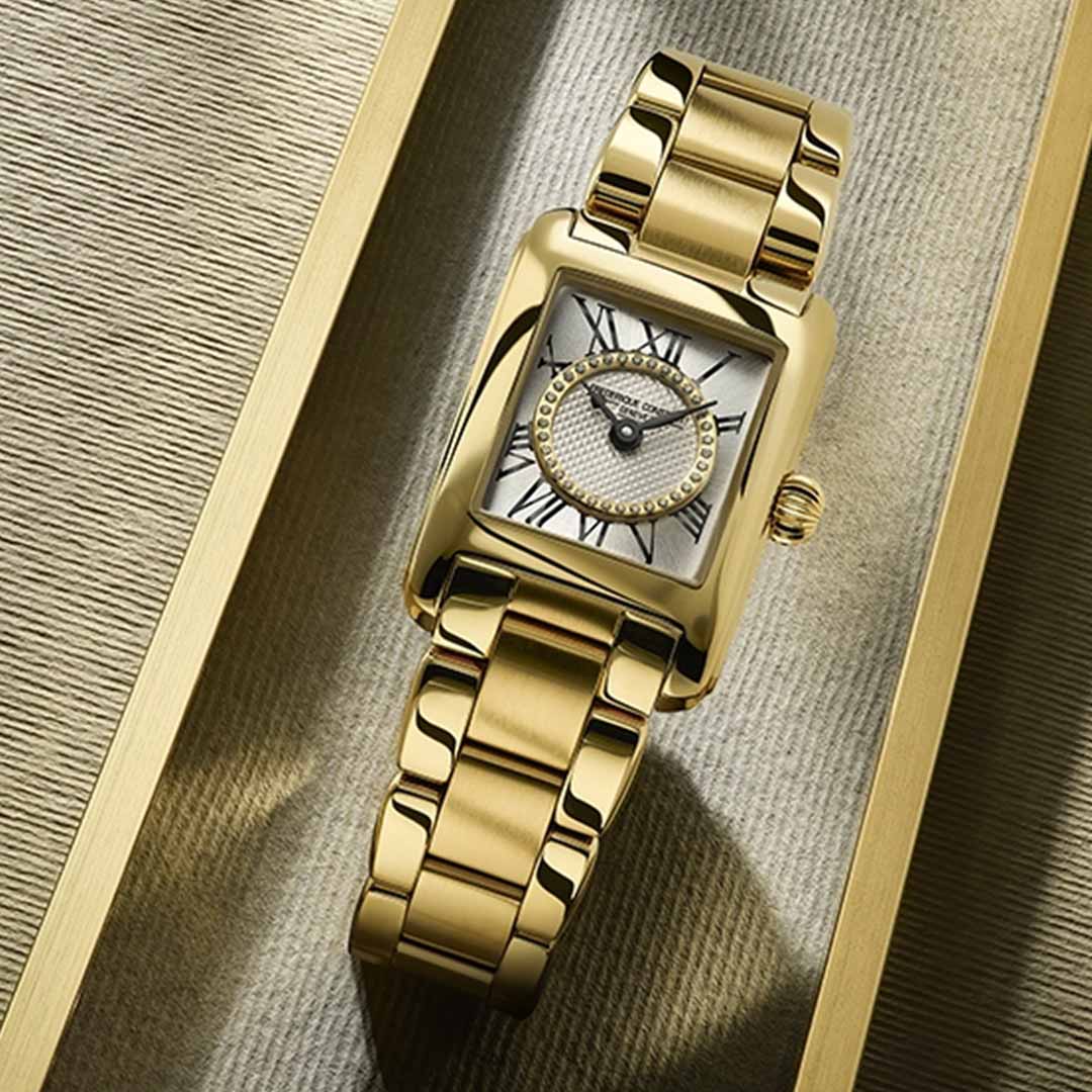 The Frederique Constant Classics Carree Ladies Quartz 30mm x 21mm Watch, crafted by Frederique Constant, showcases a gold wristwatch with an elegant polished case and Roman numeral indexes adorning a textured gold surface. It features a gold link bracelet and a decorative crown, seamlessly blending timeless sophistication with modern design.