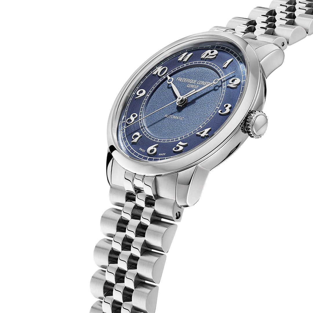 The Frederique Constant Classics Premiere Automatic 38.5mm features a silver case, blue textured dial with silver numerals, and link bracelet. Powered by the G100 La Joux-Perret movement, it is shown angled on a white background.