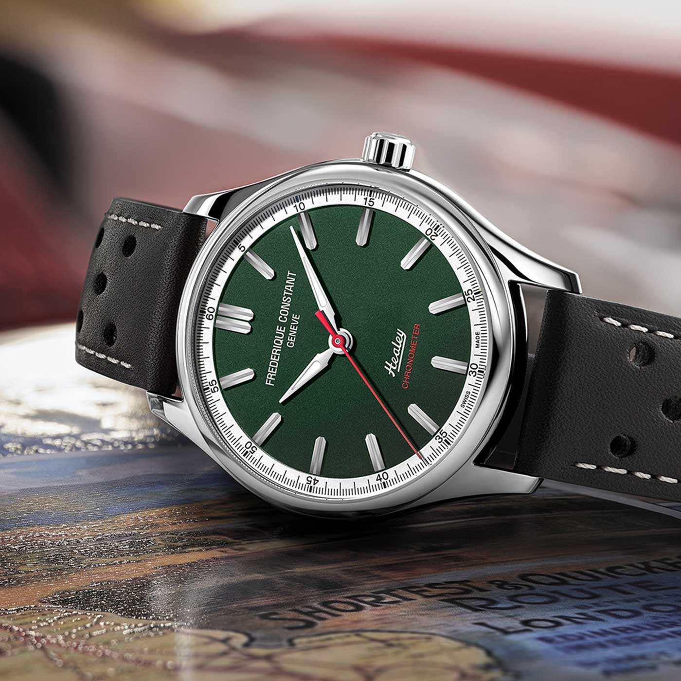 Introducing the Frederique Constant Vintage Rally Healey Automatic COSC 40mm Watch, a luxurious timepiece featuring a green dial adorned with a red second hand and the iconic "Frederique Constant" logo. This limited edition watch is designed with a stainless steel case and paired with a black leather strap highlighted by white stitching. Its presentation is completed by its display on an eye-catching map design.