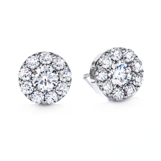 The Hearts On Fire Fulfillment Stud Earrings by Hearts on Fire showcase a pair of round diamond studs encircled by a brilliant cluster set against a gleaming white backdrop. Featuring central diamonds surrounded by smaller gems, these white gold stud earrings radiate an elegant sparkle.