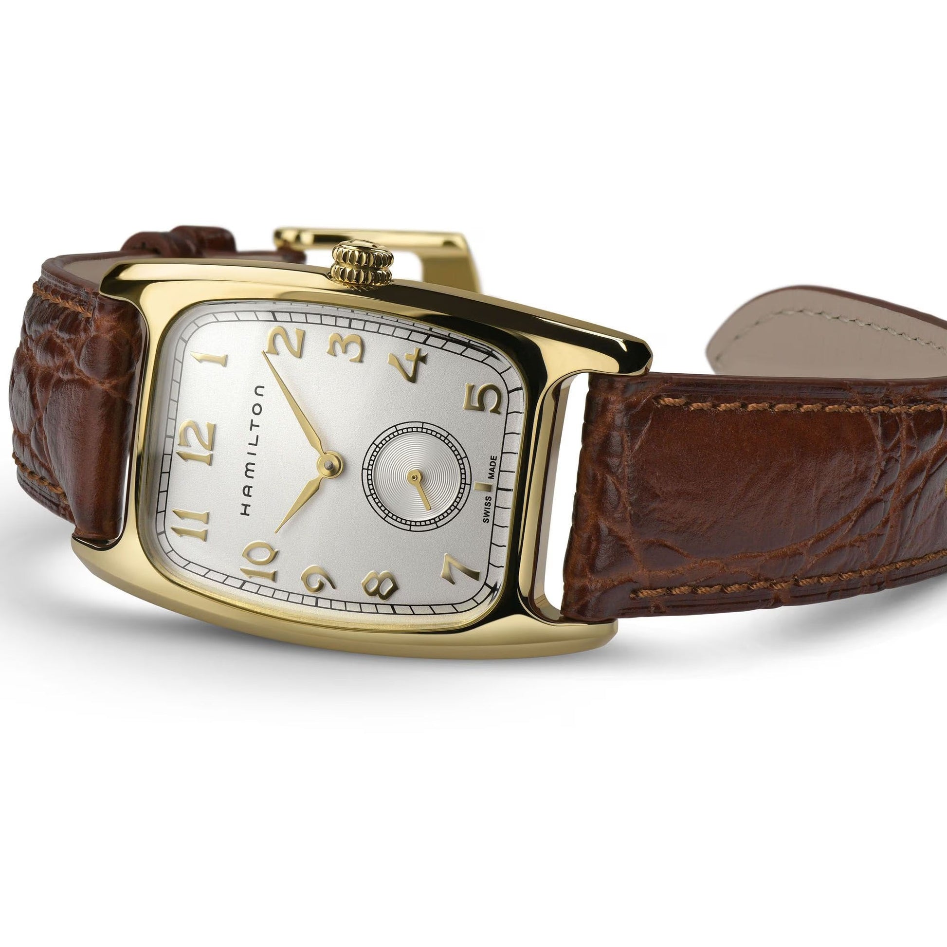 The Hamilton American Classic Boulton Quartz 27mm x 32mm Watch by Hamilton Watch, featuring a square gold case, white dial with gold Arabic numerals, small seconds subdial, and brown leather strap, is showcased on a white surface.