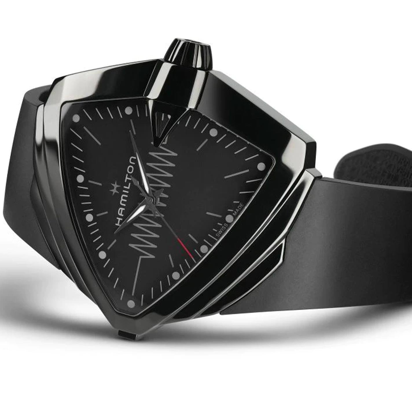 The Hamilton Ventura XXL Bright Quartz 52mm X 47.6mm Watch by Hamilton Watch showcases a black triangular design highlighted by a geometric patterned dial and complemented by a smooth black strap. Its modern and sleek look is enhanced with a uniquely shaped case and features a light-up dial for better visibility.