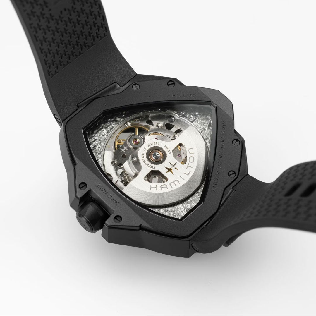 Close-up of the back of the Hamilton Ventura Edge Skeleton Automatic 51mm x 47mm by Hamilton Watch, revealing its see-through case, visible H-10-S movement, textured strap, and intricate mechanics behind the skeletonized dial.