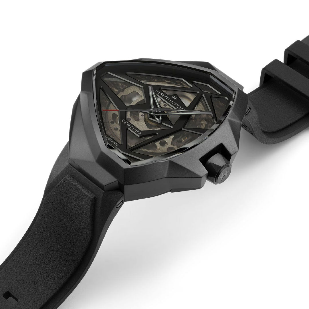 Close-up of the Hamilton Ventura Edge Skeleton Automatic 51mm x 47mm by Hamilton Watch—a modern black wristwatch with an angular case, skeletonized dial showcasing its H-10-S movement, and a textured black strap for contemporary style.