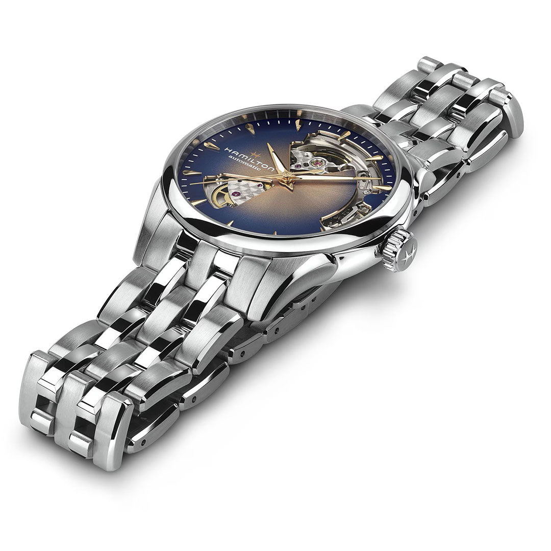 The Hamilton Jazzmaster Open Heart Lady Auto 36mm silver watch by Hamilton Watch features a blue and gold gradient dial with an exposed movement and stainless steel bracelet, shown angled on a white background.