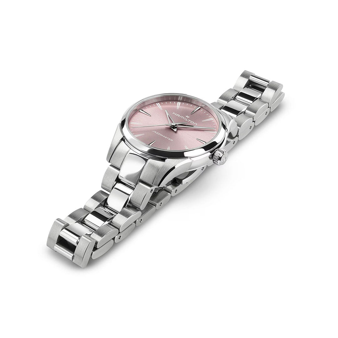 The Hamilton Jazzmaster Quartz 32mm Watch by Hamilton Watch features a silver metal case, pink dial, silver hour markers, and a 32mm stainless steel link band, shown on a white background.