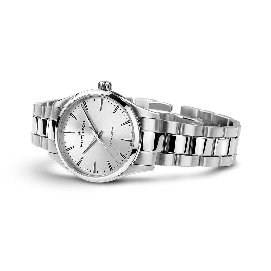 The Hamilton Jazzmaster Quartz 32mm Watch by Hamilton Watch features a silver sunray-brushed dial, slim hour markers, metal link bracelet, and single crown, shown on a white background.