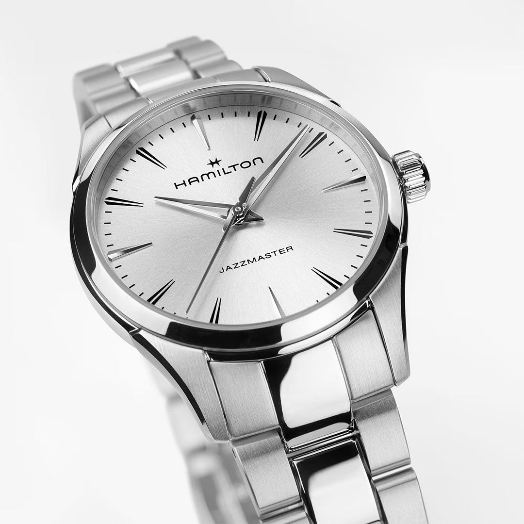 A close-up of the Hamilton Jazzmaster Quartz 32mm Watch by Hamilton Watch, featuring a silver sunray-brushed dial, slim hour markers, and a stainless steel bracelet against a white background.
