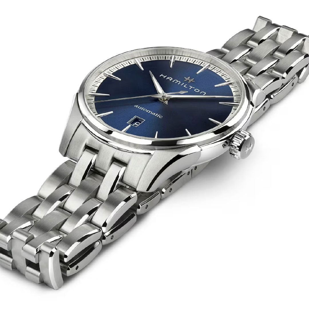 The Hamilton Jazzmaster Auto 40mm Watch by Hamilton Watch features a silver polished metal band, blue dial with silver markers and hands, an anti-magnetic alloy case, date window at 6 o'clock, and the logo below 12 o'clock.