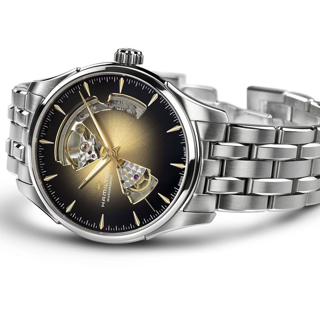 The Hamilton Jazzmaster Open Heart Auto 40mm by Hamilton Watch features a silver case, metal link band, and black-gold gradient dial with exposed mechanical gears visible through two cut-outs on the watch face.