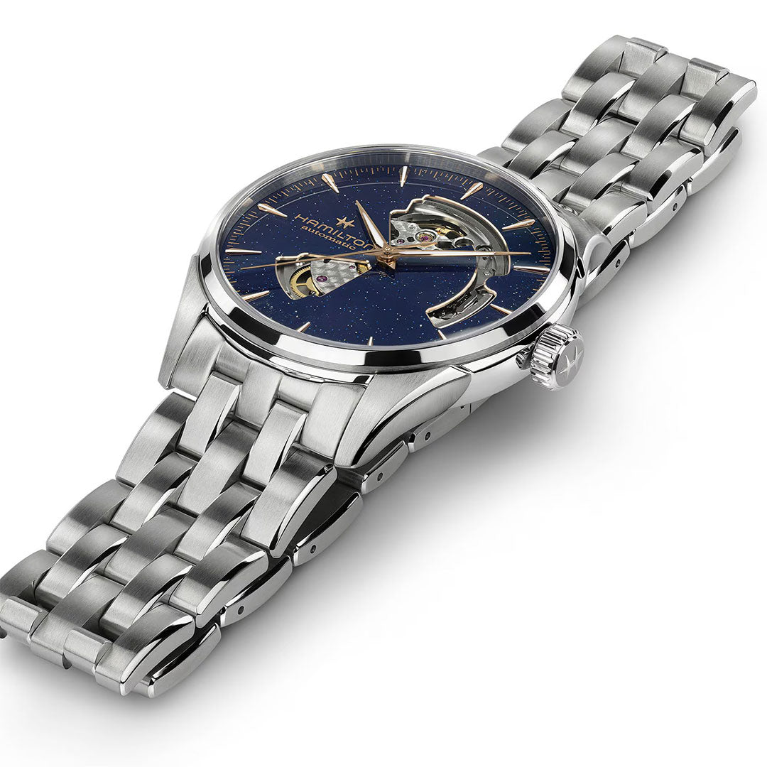 The Hamilton Jazzmaster Open Heart Auto 42mm features a silver case, blue star-speckled dial with exposed automatic movement, stainless steel bracelet, and visible right-side crown.