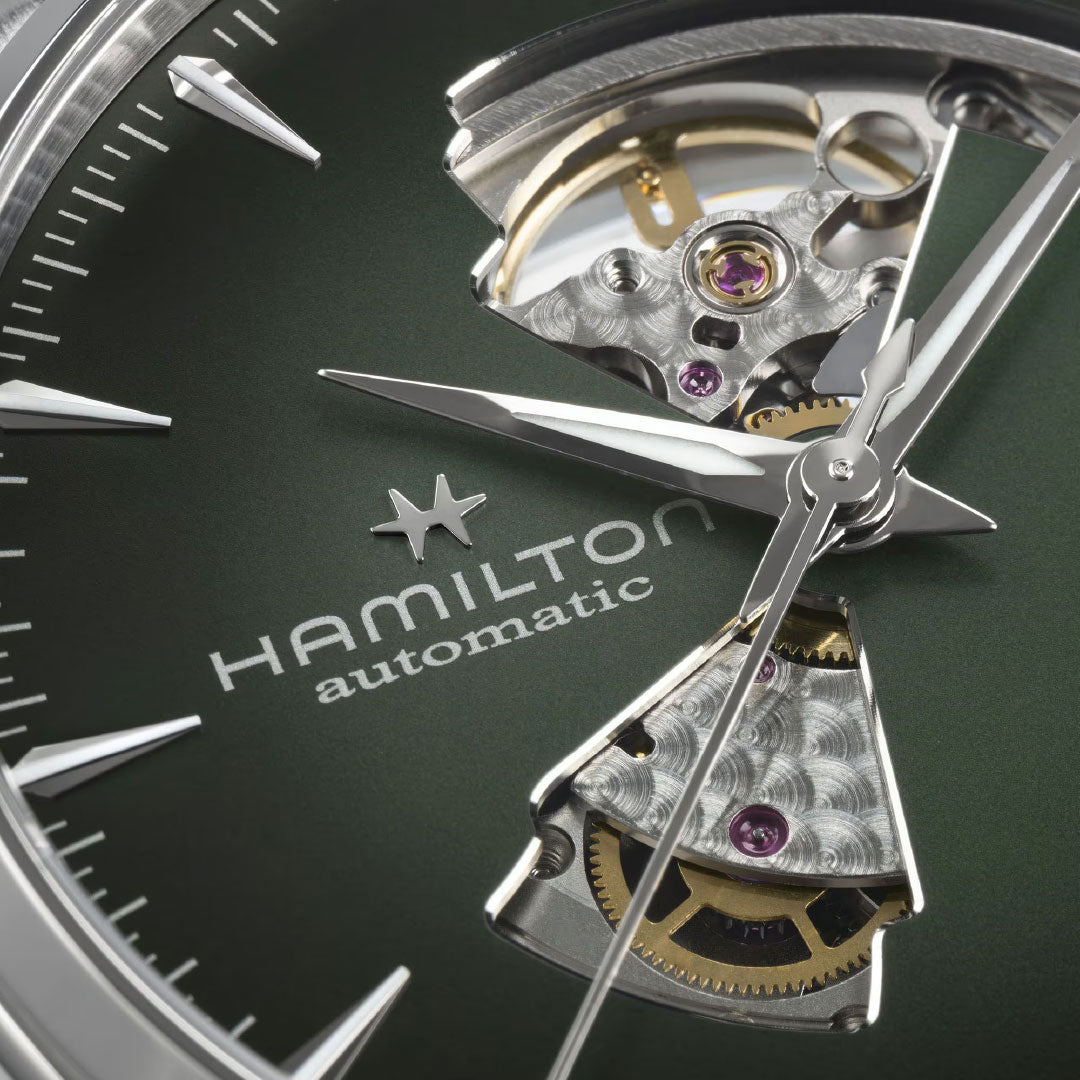 Close-up of the Hamilton Jazzmaster Open Heart Auto 42mm by Hamilton Watch, featuring a green dial, silver hands, exposed gears, and intricate automatic movement details on the branded face.