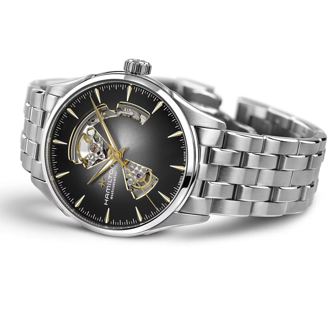 The Hamilton Jazzmaster Open Heart Auto 42mm Watch by Hamilton Watch features a stainless steel bracelet and black-gold sunburst dial with exposed mechanical movement visible through open sections on the face.