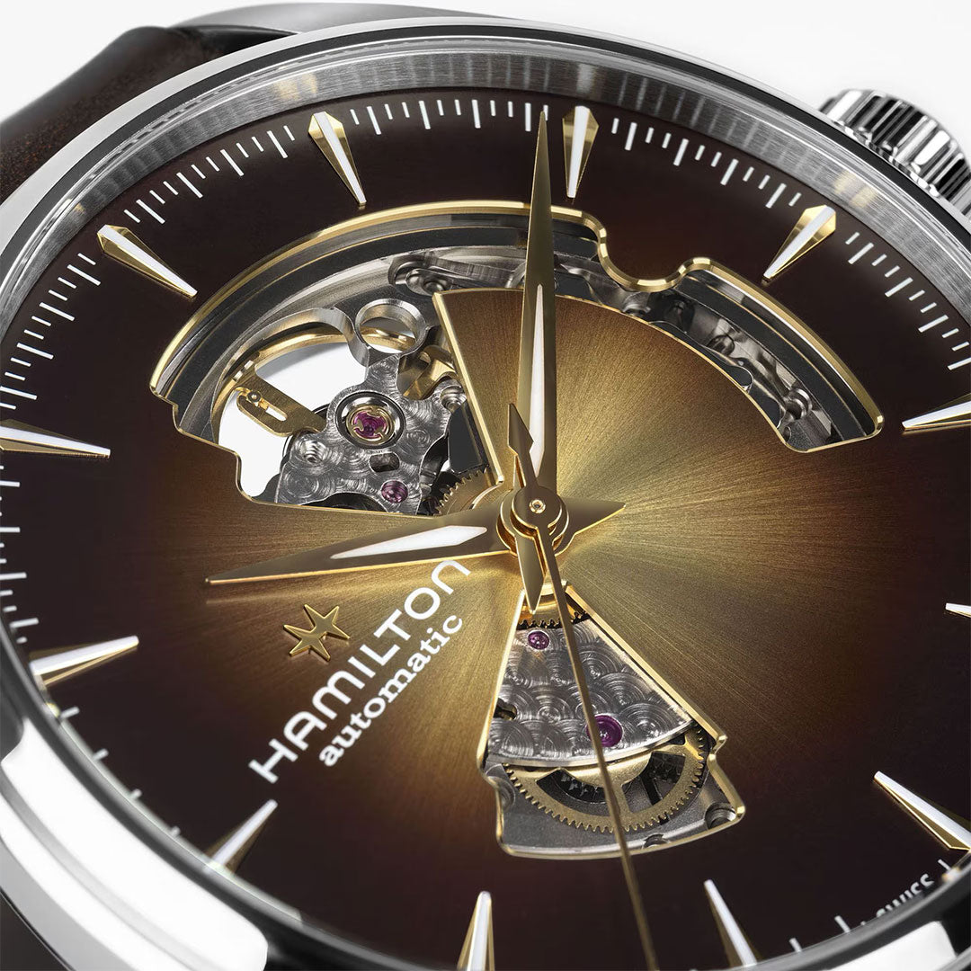 Close-up of the Hamilton Jazzmaster Open Heart Auto 42mm Watch by Hamilton Watch, featuring a brown sunburst dial, gold-tone hands and markers, an open-heart display exposing the movement, and a sophisticated brown leather strap.