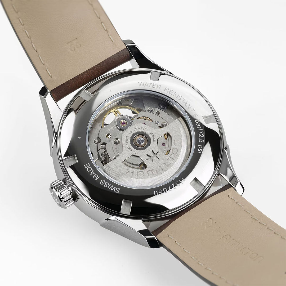 Close-up of the Hamilton Jazzmaster Open Heart Auto 42mm Watch by Hamilton Watch, featuring a brown leather strap and a transparent case back that displays its intricate automatic movement and detailed metal engraving.