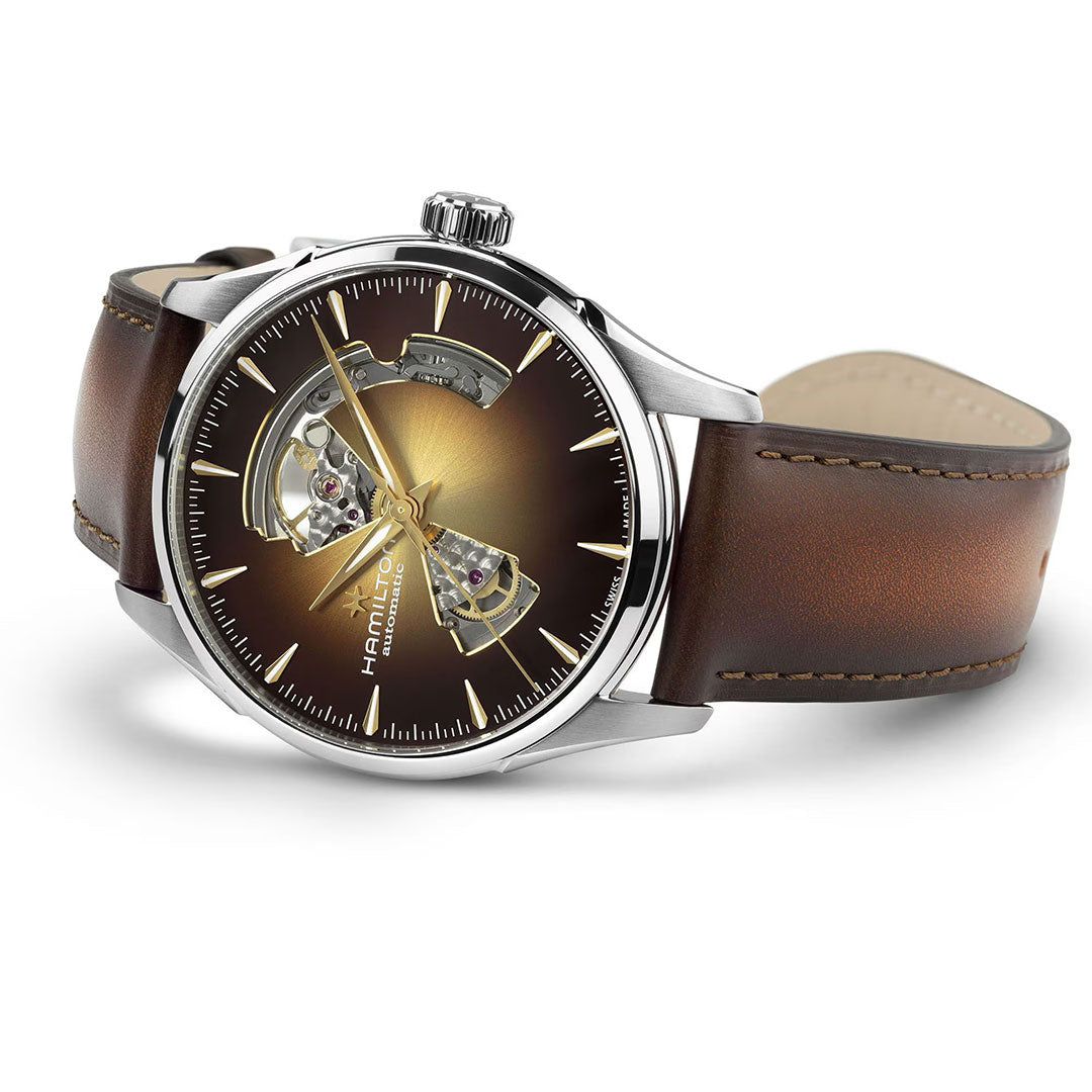 The Hamilton Jazzmaster Open Heart Auto 42mm Watch by Hamilton Watch features a brown gradient dial with partial skeleton design, silver hour markers, and a brown leather strap with visible stitching.