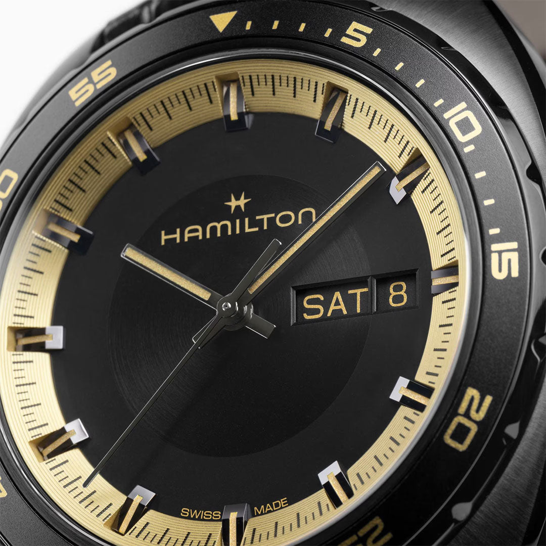 Close-up of the Hamilton American Classic Pan Europ Resident Evil Requiem Limited Edition Auto 42mm by Hamilton Watch, featuring a black and gold dial, gold hour markers and hands, day-date window showing "SAT 8," and crocodile-pattern leather strap.
