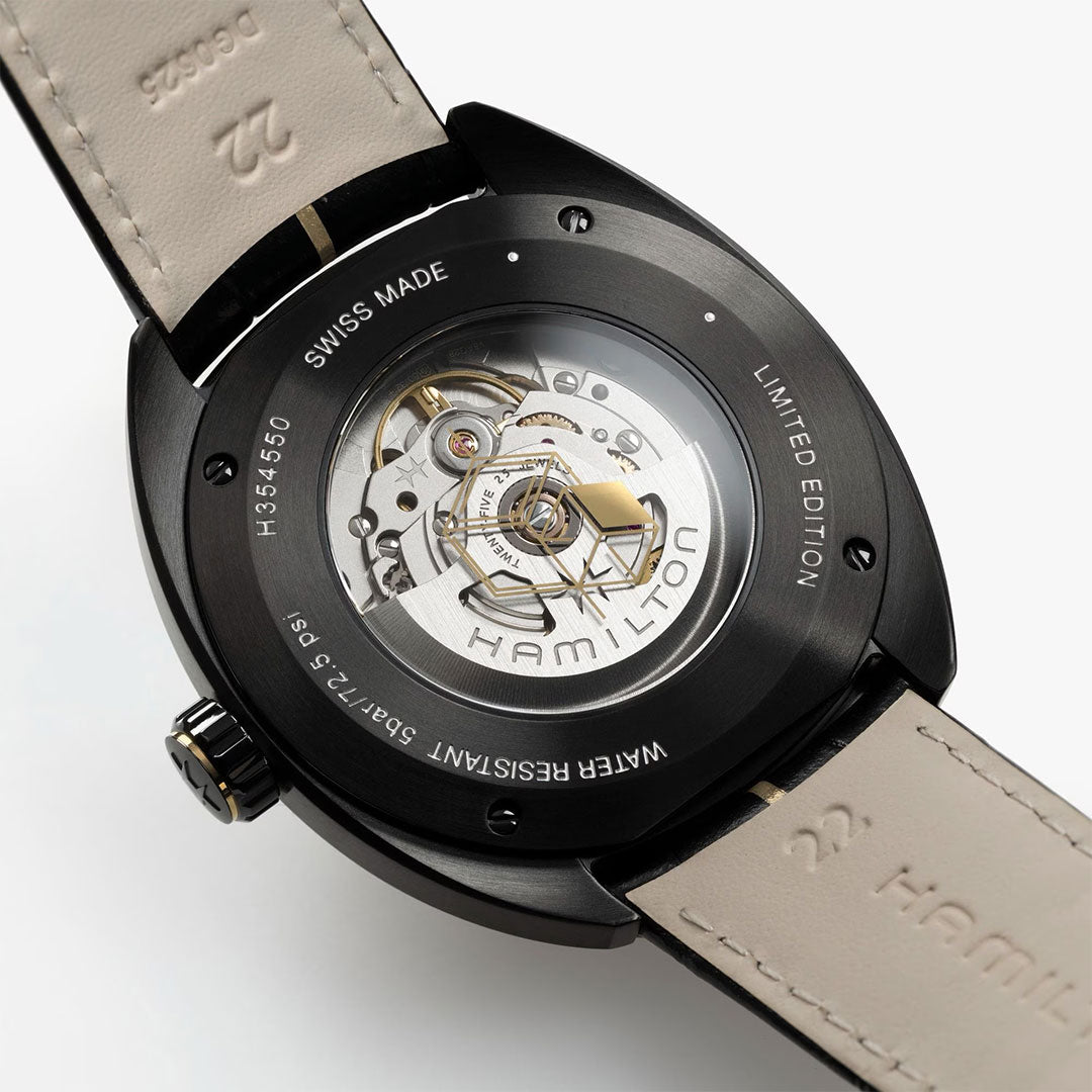 Close-up of the Hamilton American Classic Pan Europ Resident Evil Requiem Limited Edition Auto 42mm Watch by Hamilton Watch, featuring an exposed automatic movement, engraved text, and a crocodile-pattern leather strap.