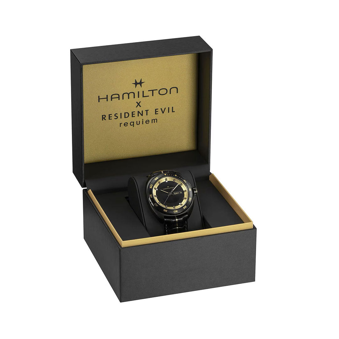 The Hamilton American Classic Pan Europ Resident Evil Requiem Limited Edition Auto 42mm watch by Hamilton Watch, featuring gold accents and a crocodile-pattern leather strap, is showcased in a black and gold box on a white background.