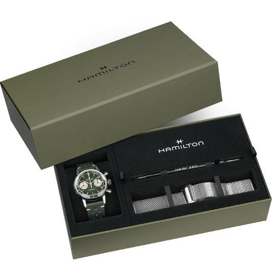 A green Hamilton gift set box with a Hamilton American Classic Intra-Matic Mechanical Chronograph H 40mm watch (two-tone, green strap), a silver mesh strap, and a strap-changing tool, all neatly arranged inside.