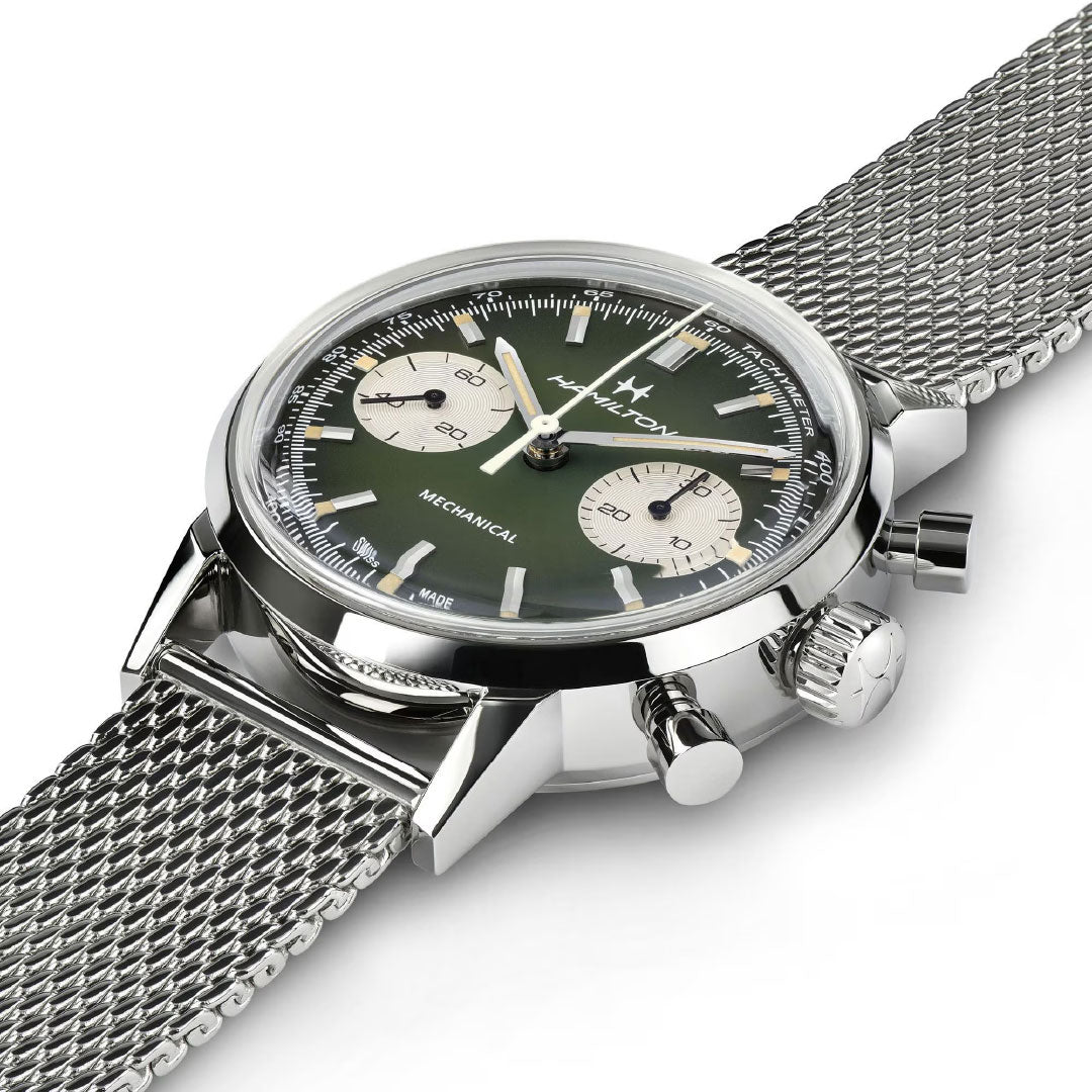 A close-up of the Hamilton American Classic Intra-Matic Mechanical Chronograph H 40mm by Hamilton Watch, featuring a green dial with two sub-dials, silver hour markers, stainless steel mesh band, and polished case inspired by vintage racing.