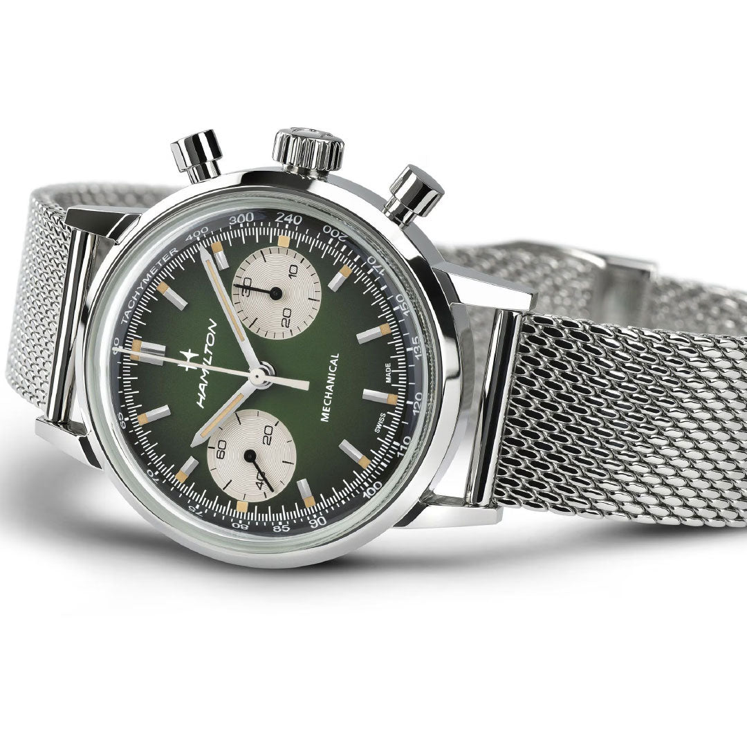 A silver mesh-band Hamilton American Classic Intra-Matic Mechanical Chronograph H 40mm features a green dial, two subdials, three pushers, and vintage-inspired chronograph details for a timeless racing style. "Hamilton Watch" is displayed on the dial.