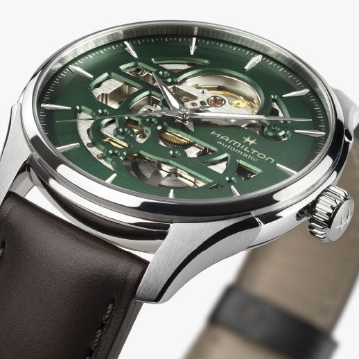 Close-up of the Hamilton Jazzmaster Skeleton Auto 40mm by Hamilton Watch, featuring a green skeleton dial that reveals internal gears, silver hour markers and hands, stainless steel case, brown leather strap, and Swiss automatic movement.