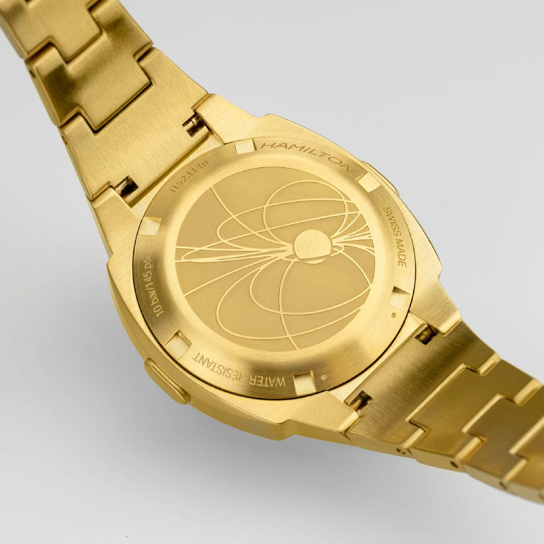 A close-up of the back of a Hamilton American Classic PSR 74 Quartz 26mm x 31mm watch, featuring an engraved planetary design and details like "SWISS MADE," "WATER RESISTANT," and model numbers on the case.