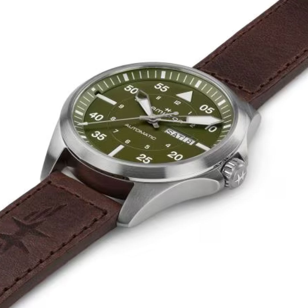 The Hamilton Khaki Aviation Pilot Day Date Auto 42mm Watch by Hamilton features a green dial with white hour and minute markers, as well as a date display. Its stainless steel case is perfectly complemented by the brown leather strap, while the automatic movement ensures that its hands and numbers stand out against the green background.