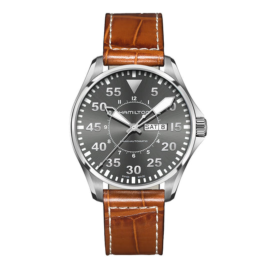 The Hamilton Pilot Day Date Auto 46mm Watch by Hamilton Watch is a silver timepiece that showcases a dark gray dial with white numerals and a brown leather strap. It features day and date windows on the right, displaying "SAT" and "8," along with three hands for the hour, minute, and second.