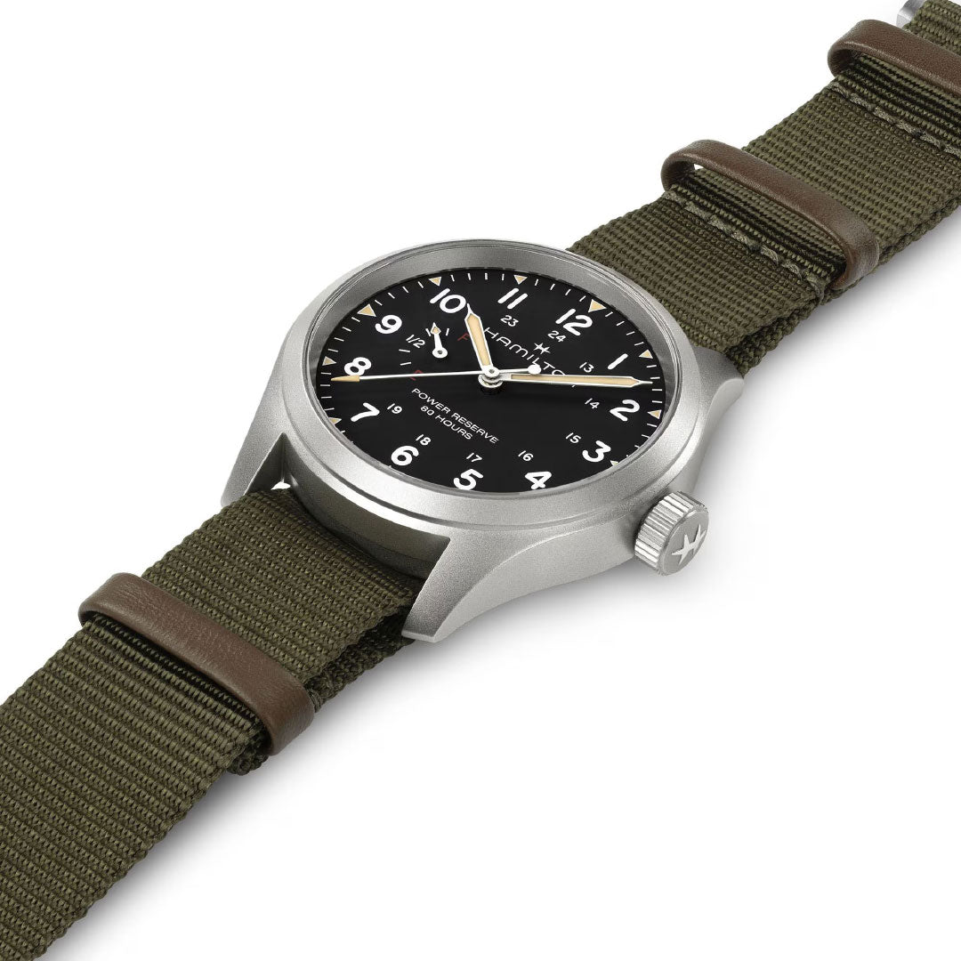 The Hamilton Khaki Field Mechanical Power Reserve 40mm Watch by Hamilton Watch features a black dial with white numerals, luminous hands, and a green fabric NATO strap with brown leather accents, shown angled on a white background.