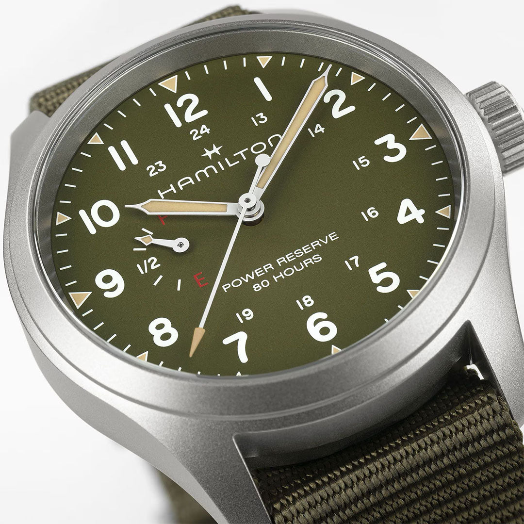 Close-up of the Hamilton Khaki Field Power Reserve Mechanical 40mm Watch by Hamilton Watch. Features a green dial, white numerals, beige hands, power reserve indicator, and green fabric strap. Display shows 10:09:37 with near-full power reserve.