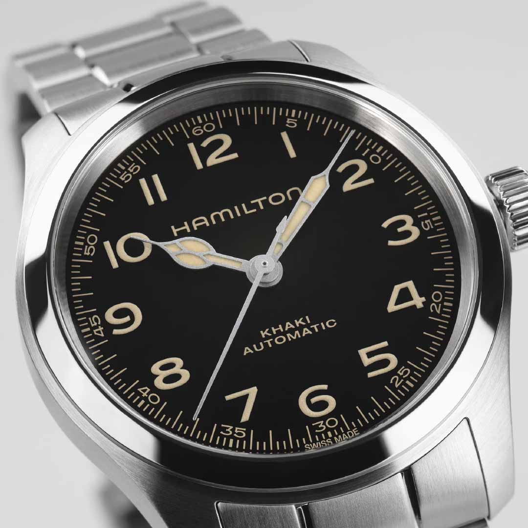 Close-up of a Hamilton Khaki Field Murph Automatic 38mm Watch, showcasing its black dial with large luminous numerals and hands. This piece from Hamilton Watch features a stainless steel case and bracelet, embodying a timeless, elegant design that captivates both long-time enthusiasts and newcomers.