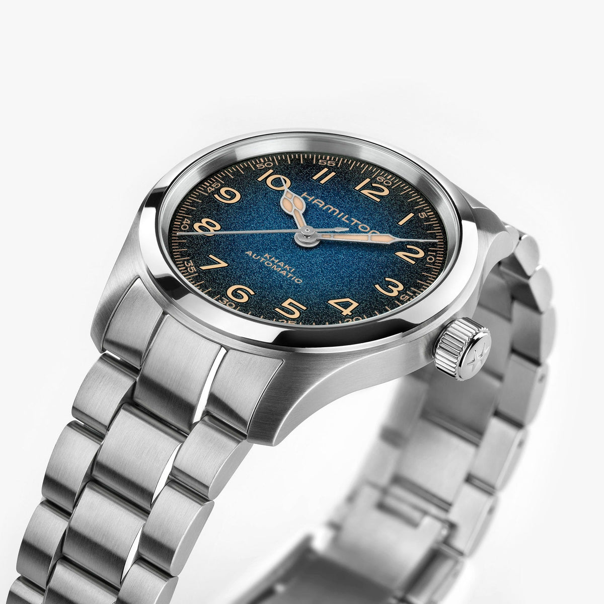 A Hamilton Khaki Field Murph Auto 38mm stainless steel wristwatch with a blue-to-black dial, gold numerals, and a metal link bracelet is shown at an angle on a white background. The “Hamilton Watch” brand name is displayed on the watch face, and this model features an automatic calibre for precise timekeeping.