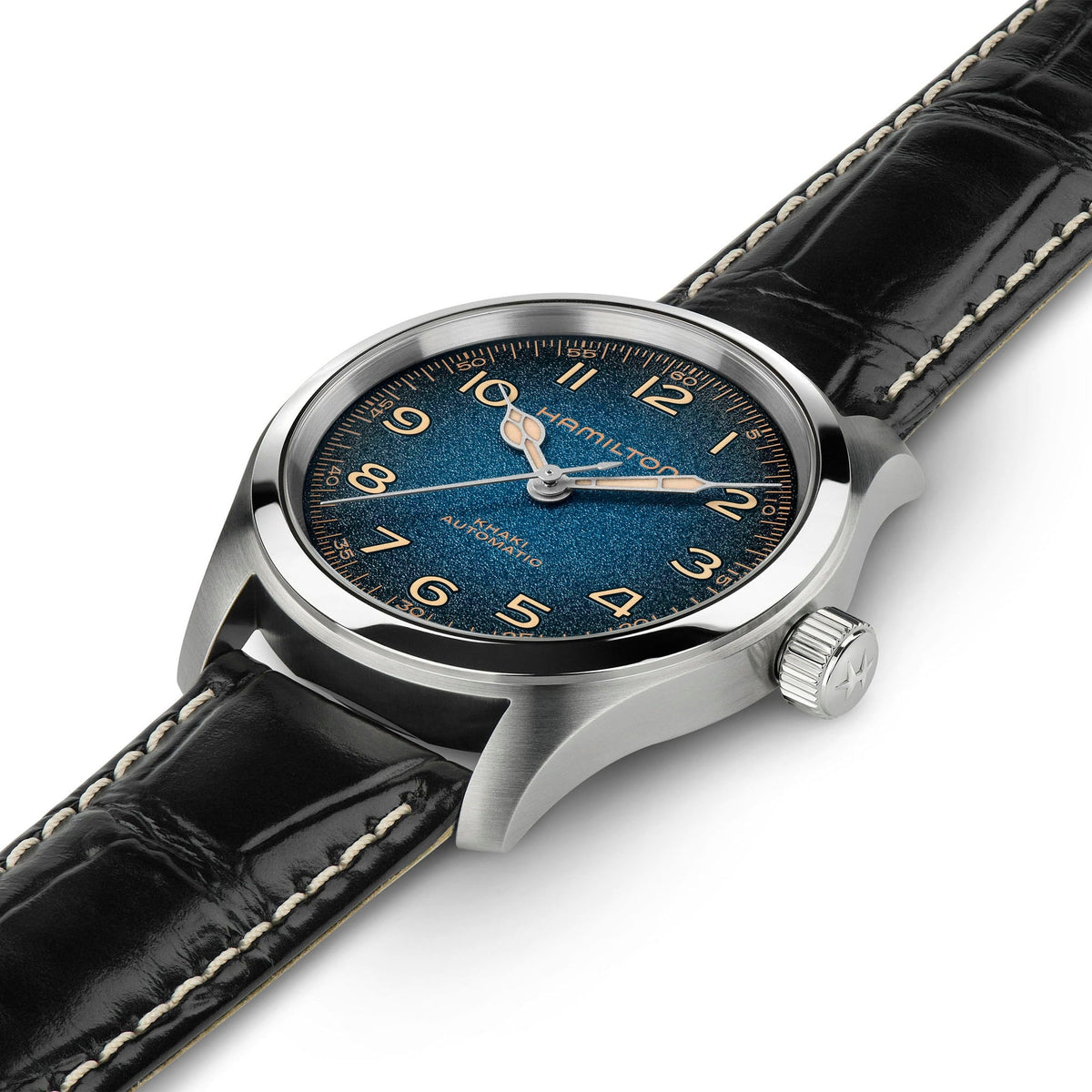The Hamilton Khaki Field Murph Auto 38mm Watch by Hamilton Watch features a blue-to-black textured dial with gold Arabic numerals, a silver case, and a black leather strap accented with white stitching. Set against a white background, this timepiece is equipped with an automatic calibre for precision timekeeping.