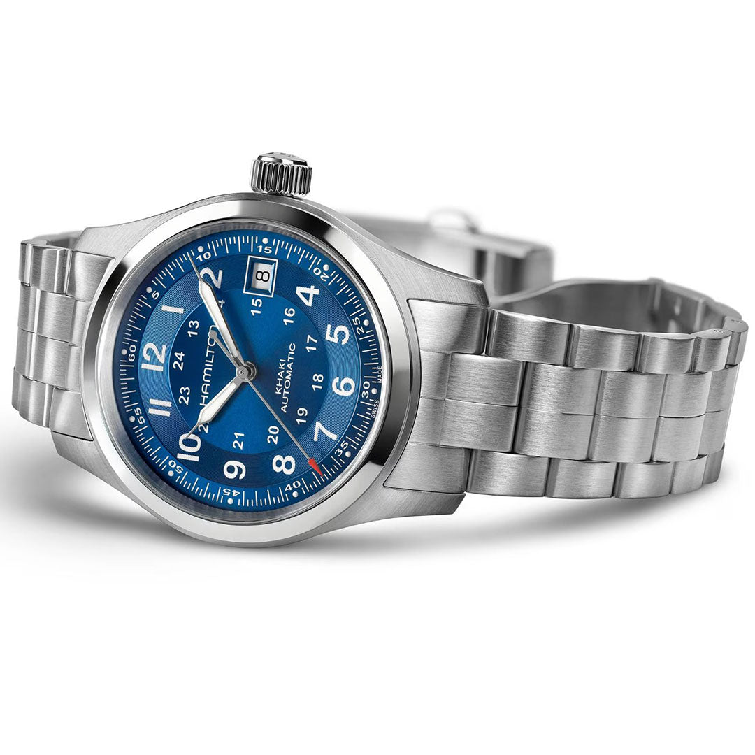 The Hamilton Khaki Field Auto 38mm by Hamilton Watch has a stainless steel case, blue dial with white markers, H-10 automatic movement, date at 3 o’clock, link bracelet, and military heritage style. It’s shown angled on a white background.