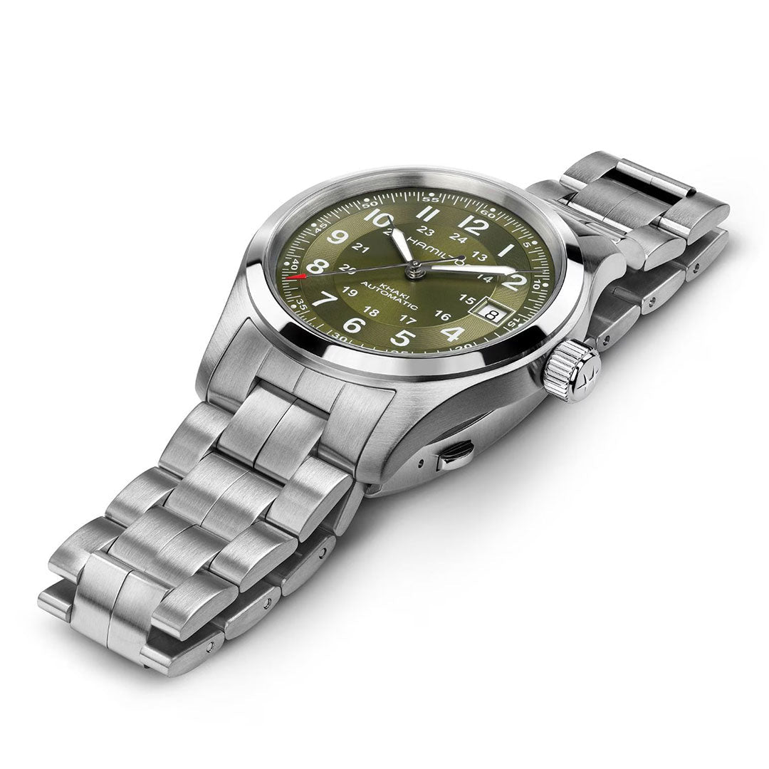 The Hamilton Khaki Field Auto 38mm Watch by Hamilton Watch features a stainless steel case, green dial with white hour markers, date window at 3 o’clock, and metal link bracelet, displayed angled on a white background with military-inspired design.