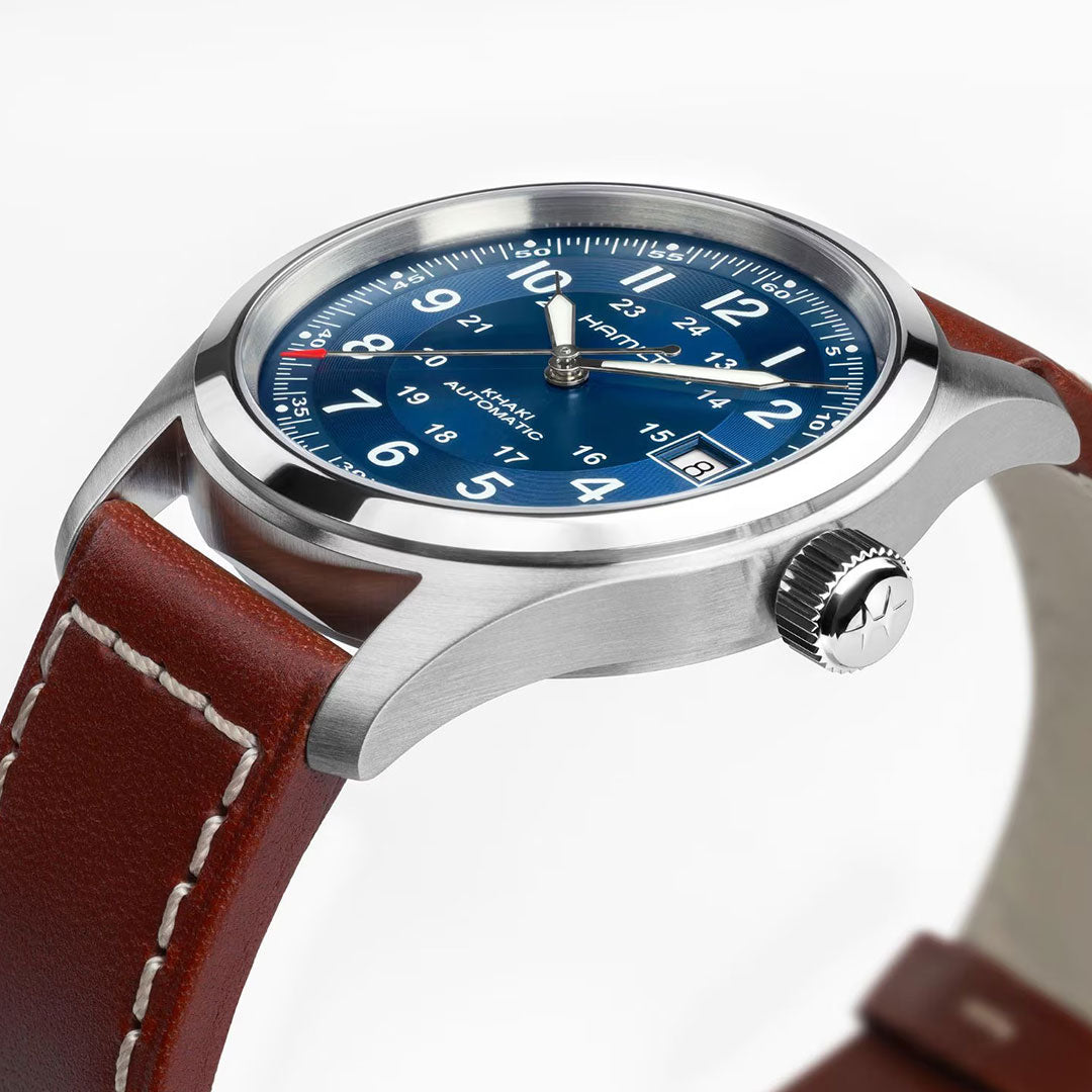 A close-up of the Hamilton Khaki Field Auto 38mm Watch by Hamilton Watch showcases its blue dial with white numerals, a date window, brown leather strap with white stitching, and reliable H-10 automatic movement, reflecting its military heritage.