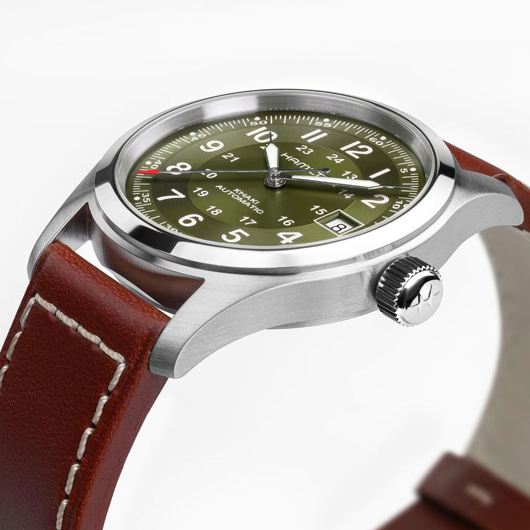 A close-up of the Hamilton Khaki Field Auto 38mm Watch from Hamilton Watch, featuring a military-inspired olive green dial, white numerals, date window, silver case, brown leather strap with white stitching, and H-10 automatic movement.