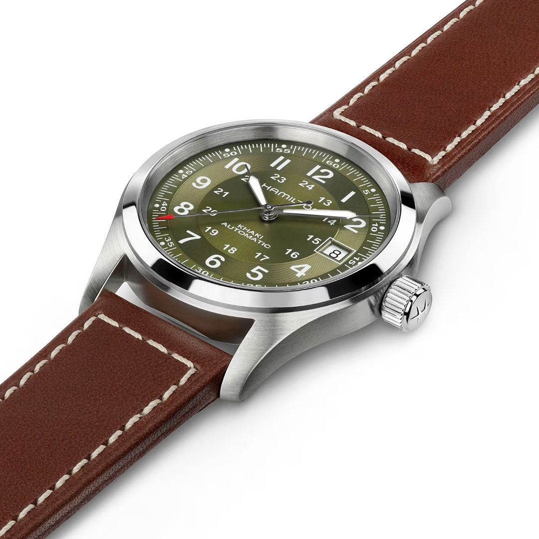 The Hamilton Khaki Field Auto 38mm Watch by Hamilton Watch features a stainless steel case, olive green dial with white numerals, and a brown leather strap with white stitching, highlighted at an angle on a white background.