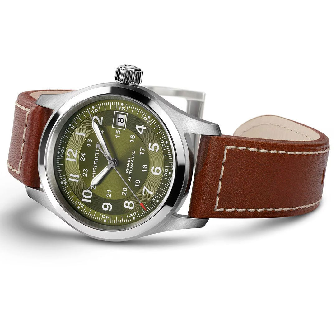The Hamilton Khaki Field Auto 38mm Watch by Hamilton Watch features a military-inspired olive green dial, white numerals, date at 3 o'clock, H-10 automatic movement, brown leather strap with white stitching, and stainless steel case.