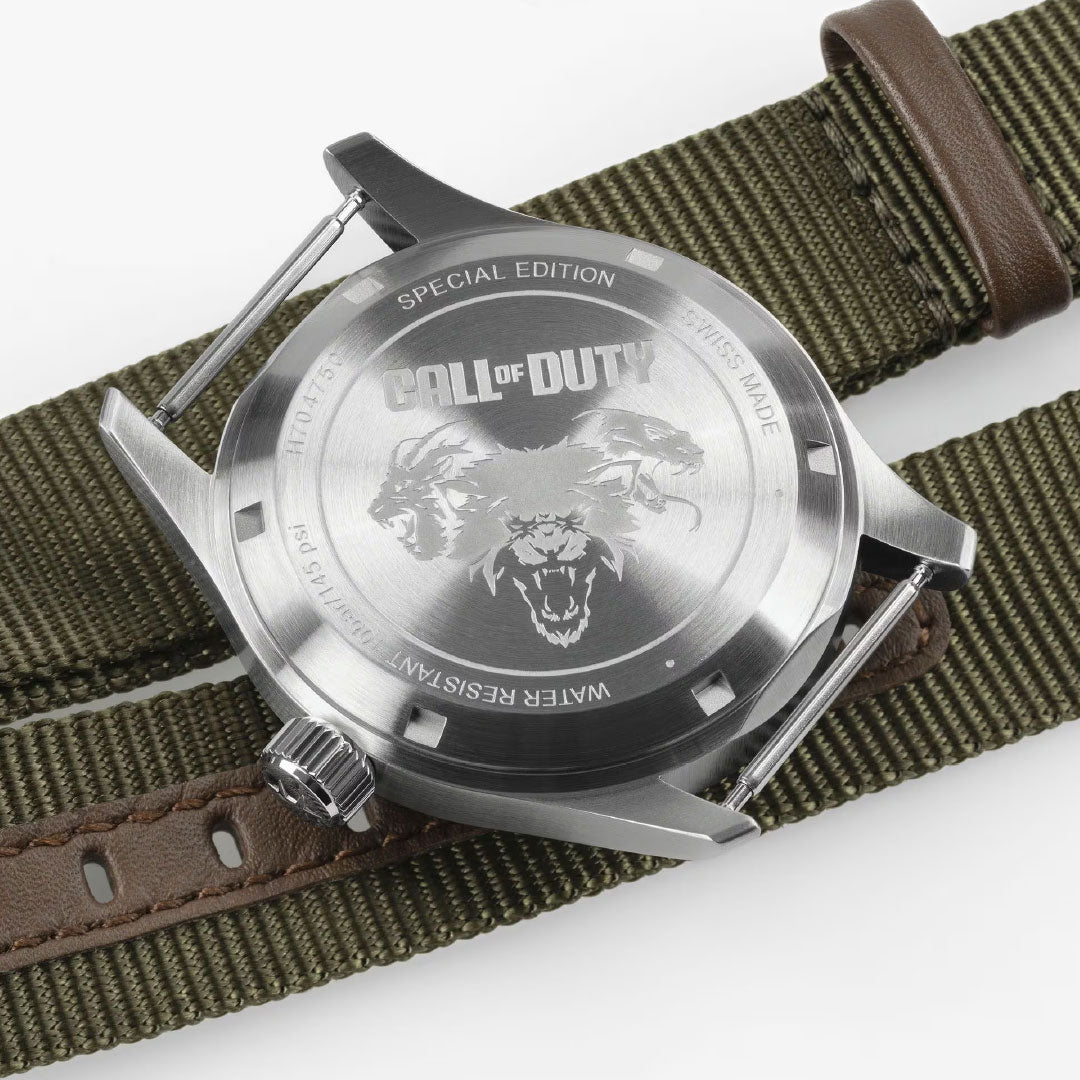 The Hamilton Khaki Field Auto 38mm Watch Call of Duty by Hamilton Watch features a Swiss-made stainless steel case back engraved with "CALL OF DUTY," a roaring lion, special edition details, and an olive green and brown fabric strap.