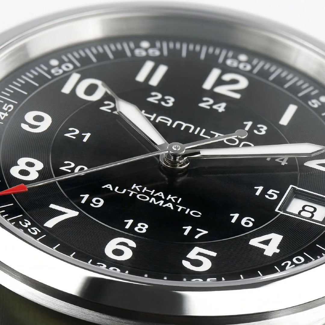Close-up of the Hamilton Khaki Field Auto 38mm Watch Call of Duty by Hamilton Watch, featuring both 12-hour and 24-hour markers, silver hands with a red-tipped second hand, and a date window at the 3 o'clock position.