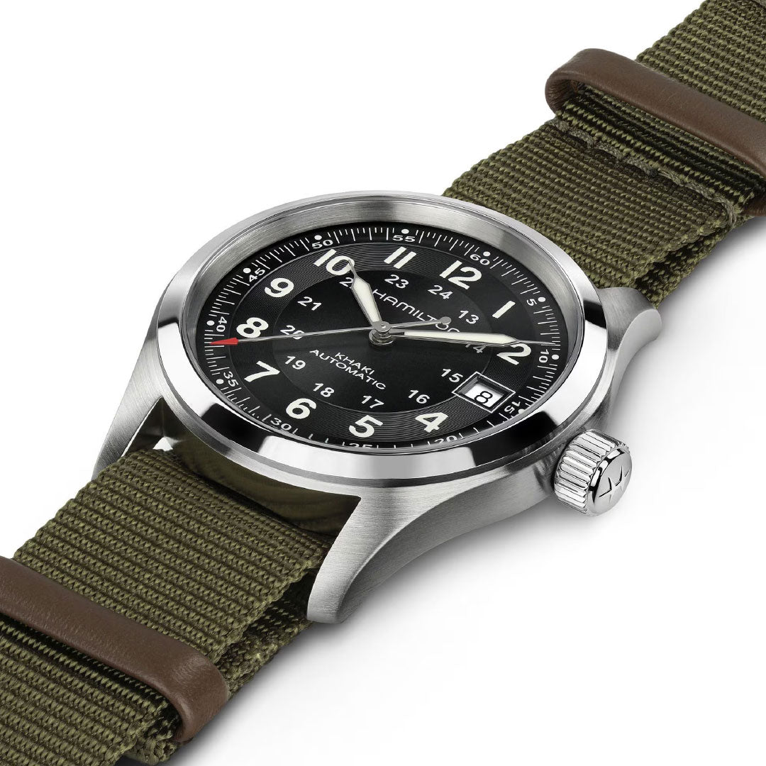 The Hamilton Khaki Field Auto 38mm Watch Call of Duty by Hamilton Watch features a stainless steel case, black dial with white numerals, and a green fabric strap with brown leather accents, shown angled on a white background.