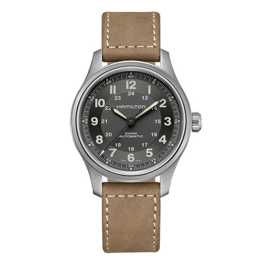 A silver wristwatch with a green dial displaying Arabic numerals and a date window, featuring the brand name "Hamilton Watch" along with "Hamilton Khaki Field Titanium Auto 42mm Watch." It boasts an 80-hour power reserve and is complemented by a beige leather strap with white stitching, giving it a touch of military style.