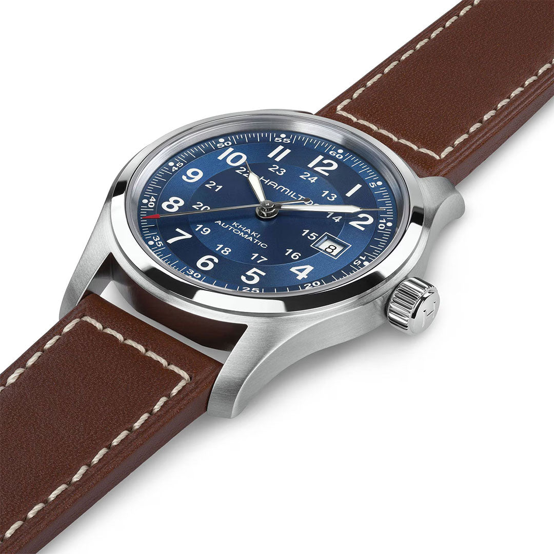 The Hamilton Khaki Field Auto 42mm Watch by Hamilton Watch features a stainless steel case, blue dial with white numerals and date display, plus a brown leather strap with white stitching—capturing classic military heritage in its design.