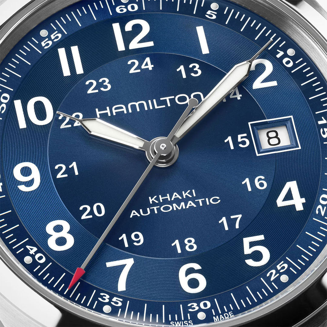 Close-up of the Hamilton Watch Khaki Field Auto 42mm’s blue dial, with silver hands, white Arabic numerals, 24-hour inner ring, date at 8th, and a red-tipped seconds hand—powered by the H-10 automatic caliber to honor its military heritage.