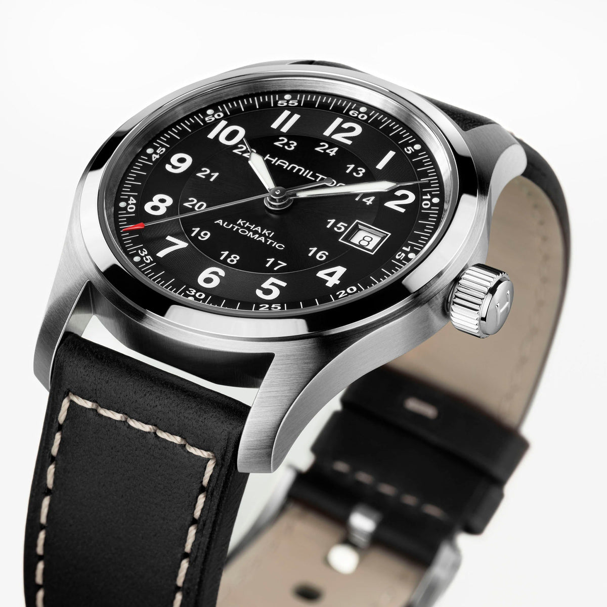 A close-up of the Hamilton Watch Khaki Field Auto 42mm features a black dial with white numerals and a black leather strap accented by white stitching, displayed at an angle. This classic timepiece from Hamilton Watch is equipped with an automatic calibre, offering reliable precision and enduring military-inspired style.